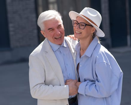 Stylish elderly laughing couple on a walk. Romantic relationships of mature people