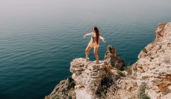 Woman travel sea. Happy tourist taking picture outdoors for memories. Woman traveler looks at the edge of the cliff on the sea bay of mountains, sharing travel adventure journey.