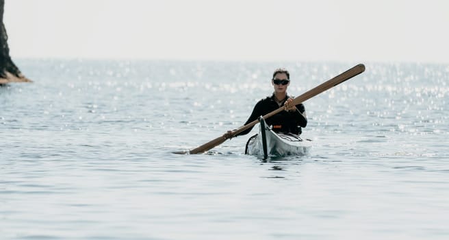 Happy smiling woman in kayak on ocean, paddling with wooden oar. Calm sea water and horizon in background