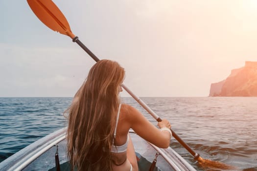 Woman in kayak back view. Happy young woman with long hair floating in transparent kayak on the crystal clear sea. Summer holiday vacation and cheerful female people having fun on the boat.