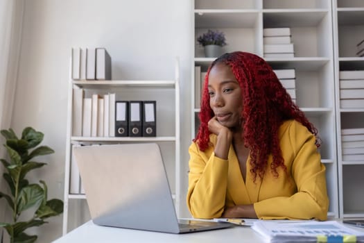 African American businesswoman is unhappy sitting on her office desk doing accounting and finance work..