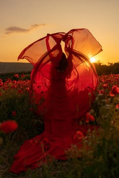 Woman poppy field red dress sunset. Happy woman in a long red dress in a beautiful large poppy field. Blond stands with her back posing on a large field of red poppies.