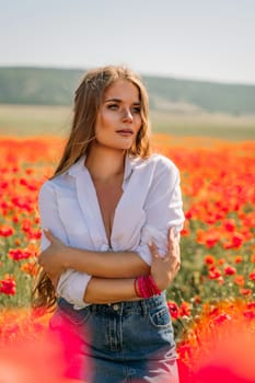 Happy woman in a poppy field in a white shirt and denim skirt with a wreath of poppies on her head posing and enjoying the poppy field