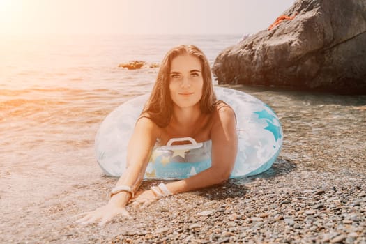 Woman summer sea. Happy woman swimming with inflatable donut on the beach in summer sunny day, surrounded by volcanic mountains. Summer vacation concept