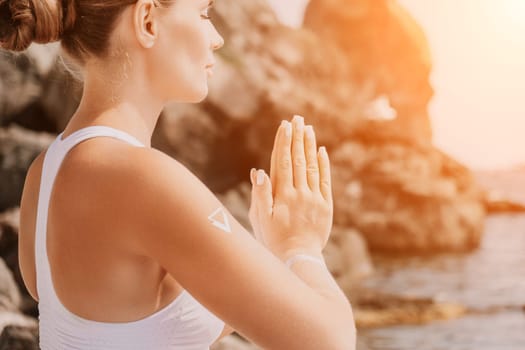 Woman sea yoga. Back view of free calm happy satisfied woman with long hair standing on top rock with yoga position against of sky by the sea. Healthy lifestyle outdoors in nature, fitness concept.