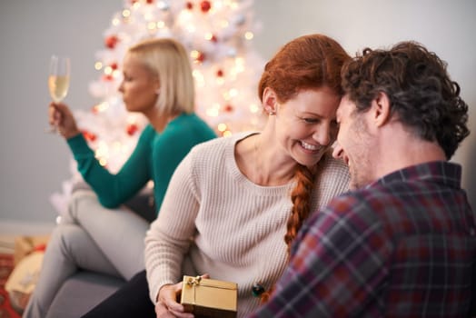 Christmas, gift and couple embrace with love for holiday in home, smile and happiness. Marriage, woman and man as husband and wife in house for celebration of festive, season and romance on vacation.
