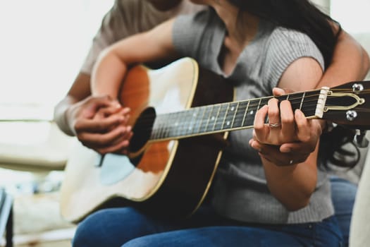 Cropped shot of young couple couple singing a song and playing guitar on sofa in living room.