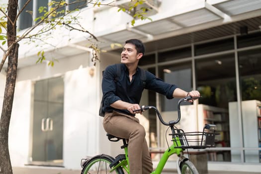 Eco friendly, Happy lifestyle asian young businessman ride bicycle go to office work at city street with bicycle in morning.