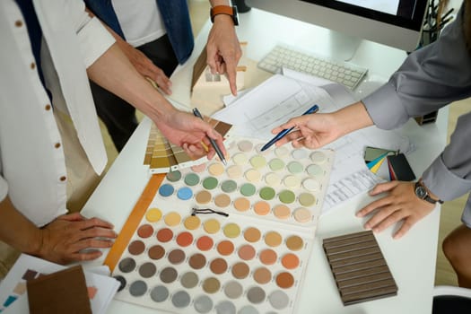 Above view of Interior designer team working with color swatches on meeting table.