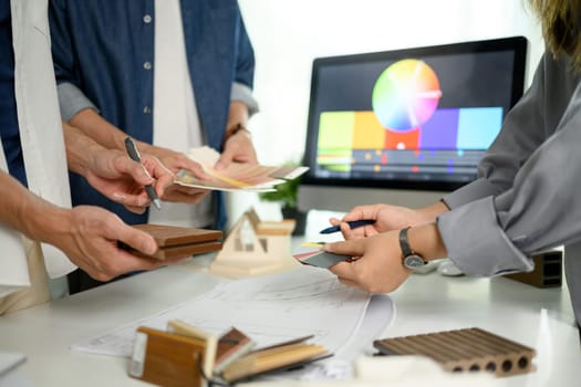 Interior designers working with material sample and color swatches on office table.