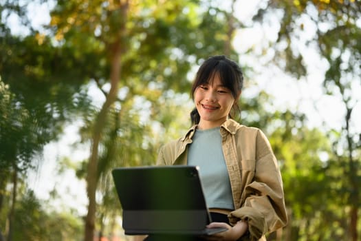 Charming young woman freelancer working with digital tablet in the city park.