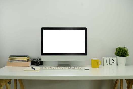 Computer monitor, camera, books and stationery on white table. Office desk.