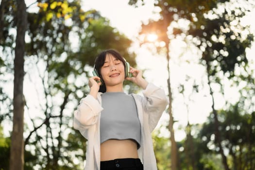 Relaxed young woman listening the music and enjoying a day in the park. Healthcare lifestyle concept.