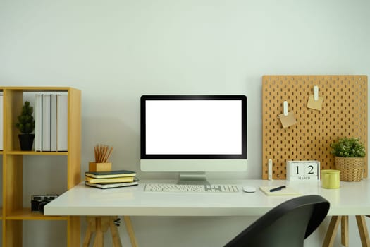 Front view of empty computer monitor and stationery on white table in home office.