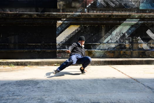 Full body of energetic street dancer dancing on city street during sunny day.