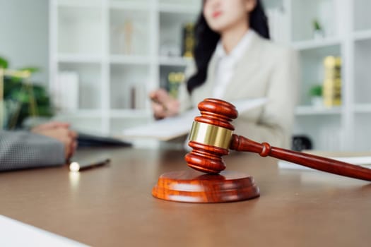 A woman is sitting at a desk with a wooden gavel on it. She is wearing a suit and she is a judge