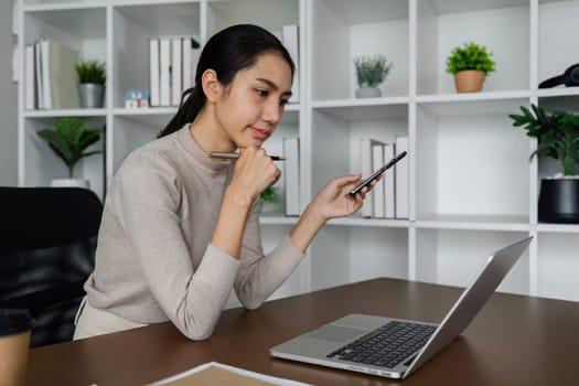 business woman using smartphone while working on laptop, synchronize data between computer and gadget in office, use corporate devices and business application.