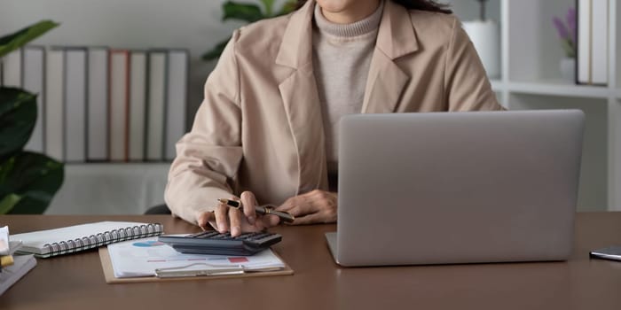 Close up business woman hand analyze to calculate the company financial and tax results the office, accounting, statistics, and analytical research.