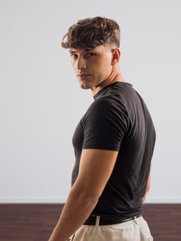 A man wearing a black shirt and khaki pants standing outdoors. He appears confident and focused as he poses for the camera.