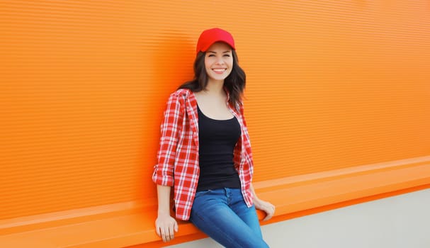 Summer portrait of happy smiling young woman posing in red baseball cap, casual clothes on city street