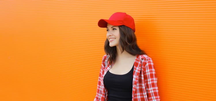Summer portrait of happy smiling young woman posing in red baseball cap, casual clothes on city street