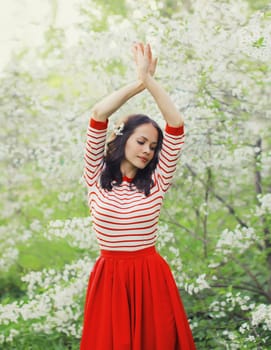 Portrait of lovely happy smiling young woman in spring blooming garden with white flowers on the trees in park