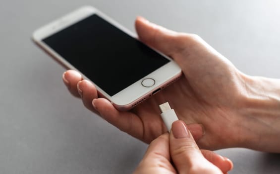 Woman hands plugging a charger in a smart phone.