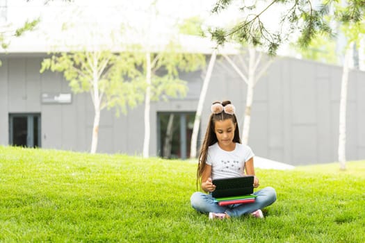 Happy little girl holding tablet PC outdoors in summer park on beautiful sunny day.