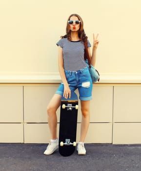 Portrait of cheerful young woman with skateboard in the city