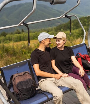 Man and a woman riding on the lift down the scenic Mountain during summer. Green tree forest surrounds the escalator