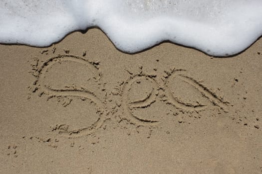 Word beach written on sand with wave coming - SEA