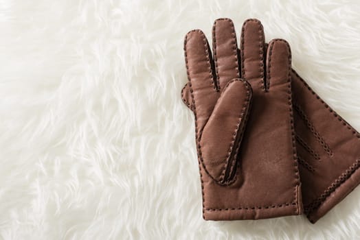 Pair of men's brown leather gloves with accent stitching in dark brown over white fur.