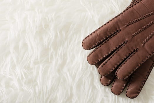 Pair of men's brown leather gloves with accent stitching in dark brown over white fur.
