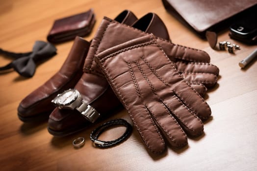 Pair of men's brown leather gloves and other men's accessories on the floor.