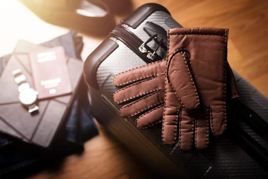 Pair of men's brown leather gloves and other men's accessories on the luggage.