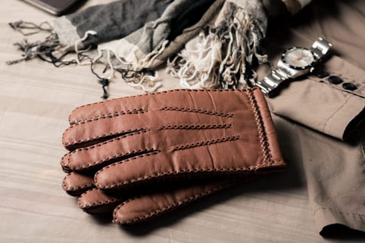 Pair of men's brown leather gloves and other men's accessories.