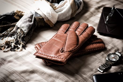 Pair of men's brown leather gloves and other men's accessories.