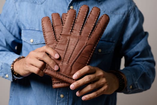 A man wearing the brown leather gloves in winter.