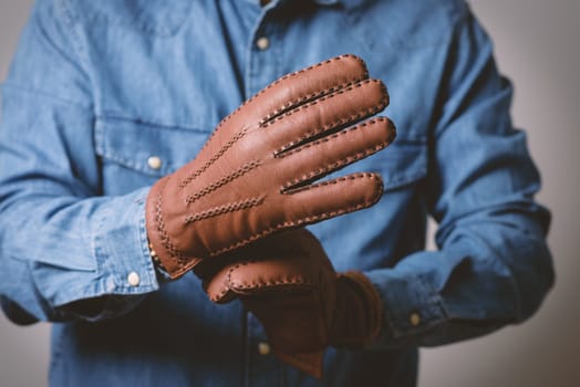 A man wearing the brown leather gloves in winter.