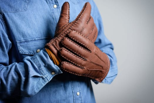 A man wearing the brown leather gloves in winter.