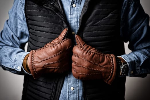 A man wearing the brown leather gloves in winter.