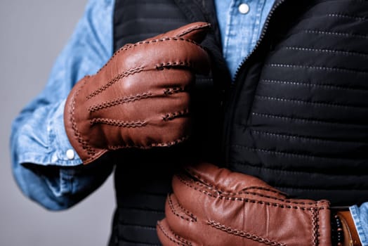 A man wearing the brown leather gloves in winter.