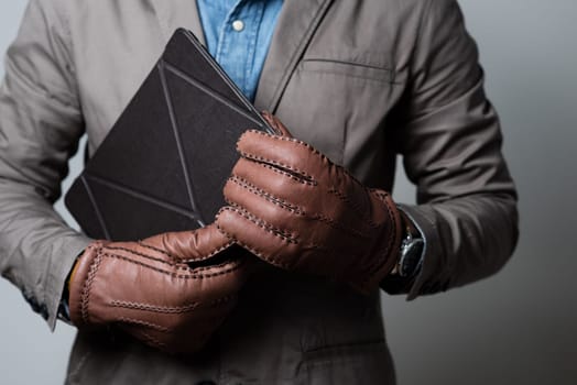 A man wearing the brown leather gloves in winter.