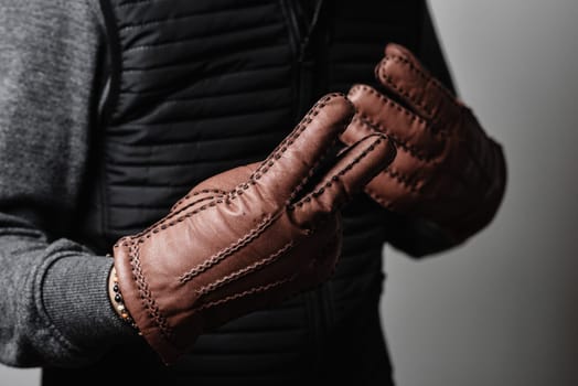 A man wearing the brown leather gloves in winter.