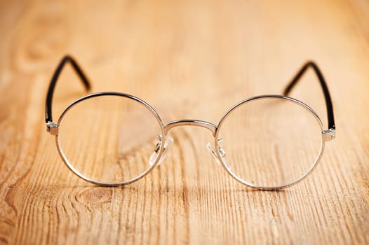 closeup round frame style of eyeglasses on wooden desk, shallow depth of field