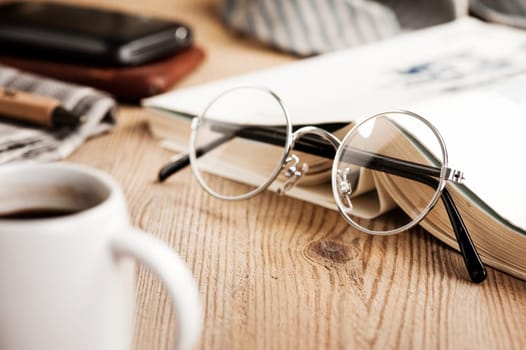 closeup round frame style of eyeglasses on wooden desk, shallow depth of field