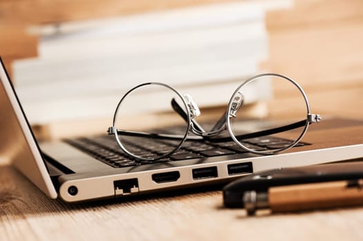 closeup round frame style of eyeglasses on wooden desk, shallow depth of field