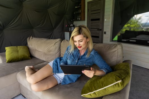 Happy young woman with tablet pc on sofa.