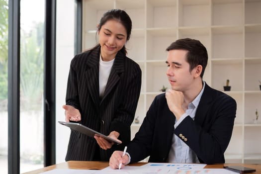 Two businessmen discussing project at the office room Businessman discusses project planning with colleagues in modern workplace while having discussion and advice on financial data report..