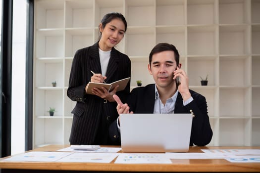 Two businessmen discussing project at the office room Businessman discusses project planning with colleagues in modern workplace while having discussion and advice on financial data report..